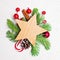 Christmas composition with empty wooden star, green fir branch, candy and holly berries on white stucco textured background.