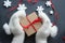 Christmas composition. Gift box with red satin ribbon holding hands in white fur mittens.