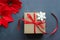 Christmas composition. Gift box with red satin ribbon, wood and snowflakes on black background. Toys Christmas decor.