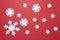 Christmas composition, group of big and small white felt snowflakes on burgundy red background. Festive, New Year concept.