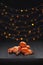 Christmas composition. Mandarins and cinnamon on black background of blurred defocused multicolor lights. Concept