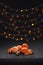 Christmas composition. Mandarins and cinnamon on black background of blurred defocused multicolor lights. Concept