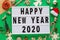 Christmas composition. Phrase Happy new year 2020 on lightbox and toys on green background. Greeting card, winter holidays, xmas
