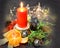 Christmas composition: a red candle burning on a festive table on a dark background. Gingerbread, tinsel, garland, mandarin.