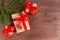 Christmas composition. Three gifts tied with a red ribbon and fir branches on a dark wooden background. Flat lay, top view. Copy