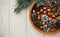 Christmas composition.Tree banch,white cones and golden acorns in the wooden plate.