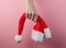 Christmas concept. Female hands hold santa hat on pink pastel background