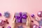 Christmas concept. First person top view photo of female hands giving lilac giftbox with ribbon bow over violet baubles snowflake