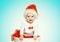 Christmas concept - happy smiling baby in santa red hat gets out of the container