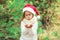 Christmas concept - little girl child in santa red hat blowing on snow in hands