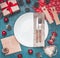 Christmas concept, postcard, gift box, Christmas toys and cones, on grey background, lined around a white plate