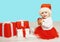 Christmas concept - smiling child in santa red hat with boxes gifts sitting on floor