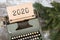 Christmas concept - typewriter with the inscription "2020" and spruce branches on a wooden table