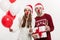 Christmas Concept - Young caucasian couple holding gifts,champagne and balloon making funny face on Christmas