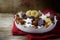 Christmas cookies and sweets like homemade cinnamon stars, marzipan balls, chocolate and biscuit in a pottery crown bowl on a red