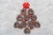 Christmas cookies tree made by cinnamon with a red star on top on a snowy background