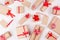 Christmas craft paper gifts with red ribbons and bows as festive pattern on soft white wooden background.