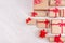 Christmas craft paper gifts with red ribbons and bows on soft white wood table, top view, border.