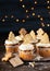 Christmas cupcakes sweet dessert with cookies topper, wooden background with garland lights bokeh. Copy space, Close up. Christmas