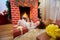 In Christmas curly little girl lying near the fireplace with gif