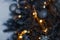 Christmas dark blurred background with a black Christmas tree, ornaments and bokeh lights