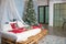 Christmas decor in the bedroom in the loft style. The bed is made of wooden pallets with white linen and red blankets and pillows.