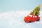 Christmas decor - a red retro car on artificial snow carries a Christmas tree with gift boxes on the roof. Toy with sequins on a