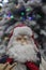 Christmas decor skiing santa in cable knit sweater in front of bokeh flocked Christmas tree - selective focus