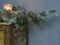 Christmas decoration candle in glass and decorated silver on spruce tree branch on old painted dresser on gray plaster background