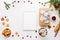 Christmas decoration, cup of coffee, homemade sweet gingerbread cookies, gift, notepad, pine cones and branches on white wooden