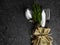 Christmas decoration. Festive cutlery with Christmas decoration as burlap bag with golden bow, white wooden star, green branch.