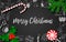 Christmas decoration with fir tree, holly berry, candy cane, lollypop on black chalkboard