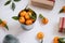 Christmas decoration of mandarin in an iron small bucket, Christmas tree, gifts on the white wooden boards background.