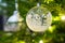 Christmas decoration ornaments  from glass with white and silver hanging in a christmas tree with lights