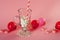 Christmas decoration on pink background. Candy with christmas ornaments. Glass cup with paper striped straw and marshmallow