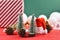Christmas decoration with small pine trees, fir cones, snatda hat and white baubles and gift box in  background