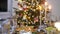 Christmas decoration with three silver candles on celebration table at christmas tree with balls and garland on blurry