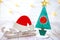 Christmas decoration on wooden background over white wall, close-up. Wooden christmas tree with Santa Claus hat on wooden sled