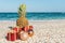 Christmas decorations, baubles and pineapple on a sandy beach on a bright and sunny day. New Year concept