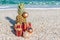 Christmas decorations, baubles and pineapple on a sandy beach on a bright and sunny day. New Year concept