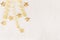 Christmas decorations, curl ribbon and gold stars falling on soft white wooden background.