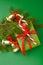 Christmas decorations and holiday wrapped gift box on green background, top view