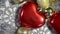 Christmas decorations move slowly clockwise. A red heart, silvery snowflakes, golden balls and silver Christmas tinsel lie in a