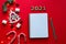 Christmas decorations and notebook for writing goals or results of the year on bright red background. New Year goal list 2021. Top
