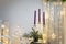 Christmas decorations. Purple candles in candlestick, fir tree branches and cones, siver curtains with shiny stars and garland