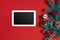 Christmas decorations and white tablet with black screen on hot red background. Christmas and New Year theme. Place for