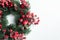 Christmas decorative wreath of holly, ivy, mistletoe, cedar and leyland leaf sprigs with red berries over white background