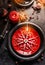 Christmas dinner table setting with red and black plates, decorated with snowflakes, burning candles and fairy lights on dark