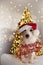 CHRISTMAS DOG PORTRAIT. FUNNY JACK RUSSELL PUPPY WEARING RED SANTA CLAUS HAT AND A MERRY CHRISTMAS SIGN UNDER CHRISTMAS TREE