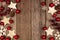 Christmas double side border with wood star ornaments and red baubles, top view over rustic wood
